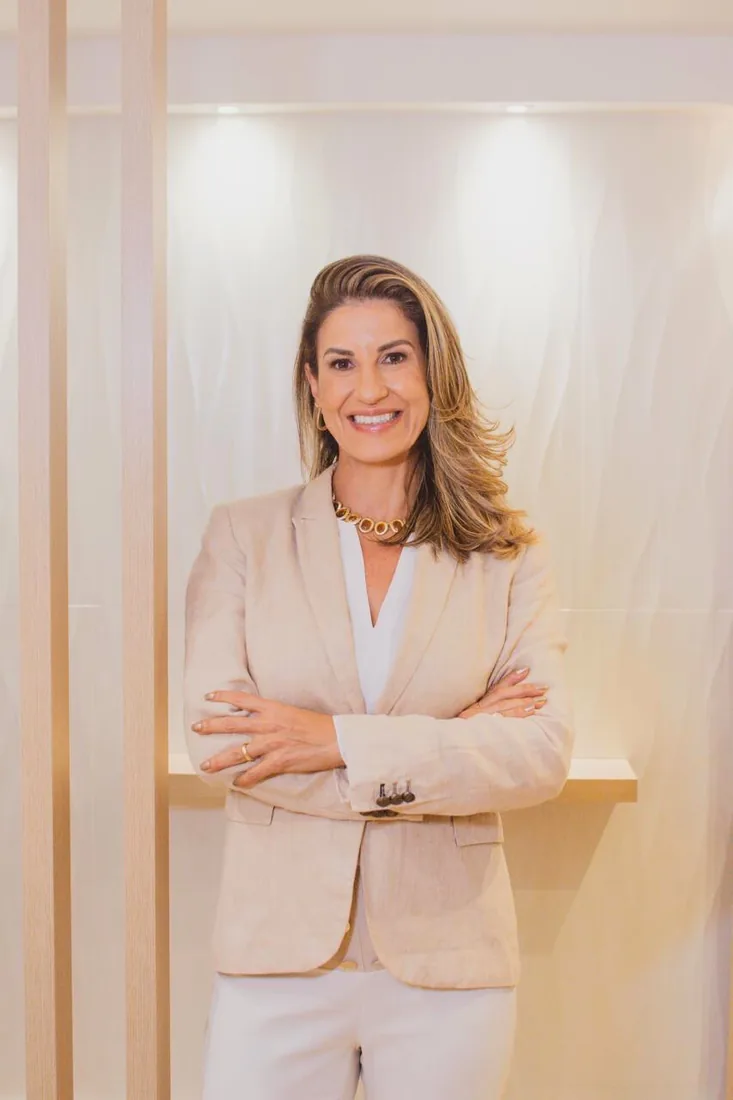 Dra. Juliana Sales de blazer bege, com os braços cruzados